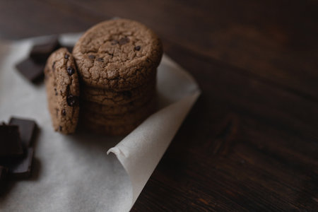 Oatmeal cookies and pieces of chocolate on dark wooden background