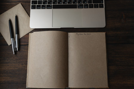Craft notebook with the words My plans for 2021 with a pen next to a laptop