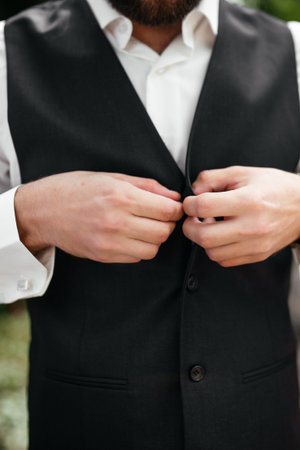 The groom buttons his jacket with friends