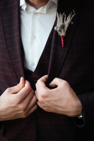 The groom buttons his jacket in room