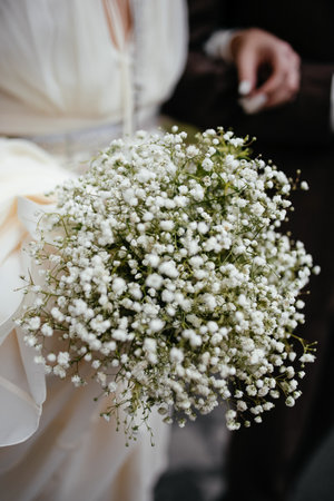 woman bride in wedding dress holding white bouquet in hand