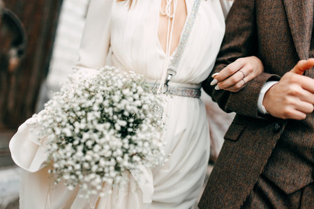 woman bride in wedding dress holds the arm of the groom on the streetの写真素材