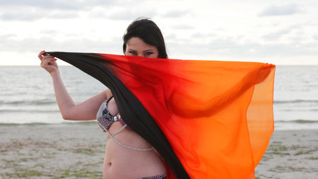 Beautiful woman with silk scarf by the seaside.の写真素材