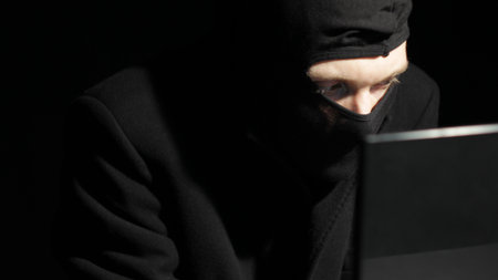 Hacker in balaclava mask in darkness low key.