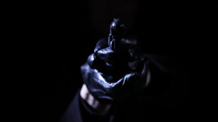 Hand with a gun in gloves low key.の写真素材