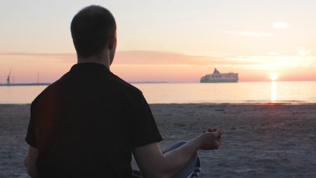 Young man meditating by the seaside at sunset.の写真素材