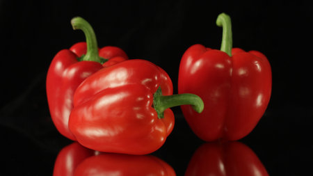 Red paprika reflecting on black background.
