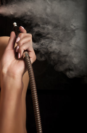 Beautiful woman smoking a hookah and smoke issues from the mouth