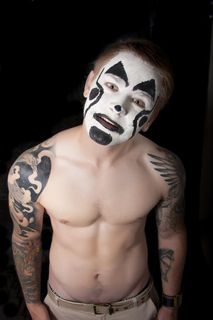 pumped up young man with tattoos and painted faceの写真素材