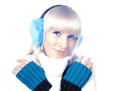 Beautiful blonde in a warm jacket, warm gloves and fur earmuffs