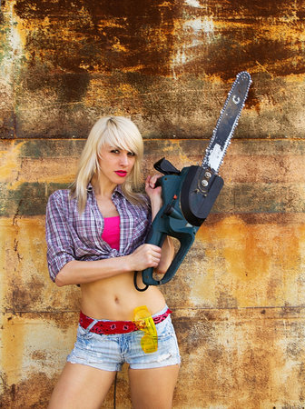 A girl with a chainsaw on a background texture rusty wallの写真素材