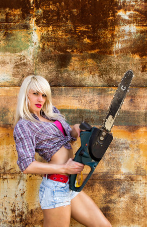 Sexy blonde girl builder with a chainsawの写真素材