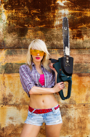 A girl with a chainsaw on a background texture rusty wallの写真素材