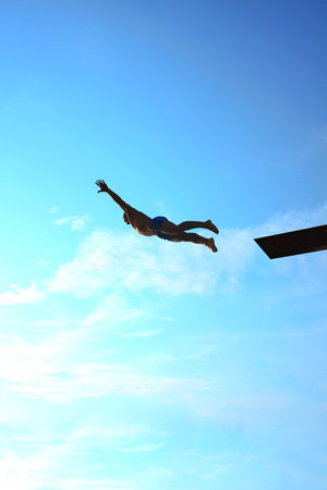 man makes a jump into the water from a springboard の写真素材