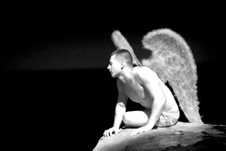 Muscular man with angel wings on the beachの写真素材