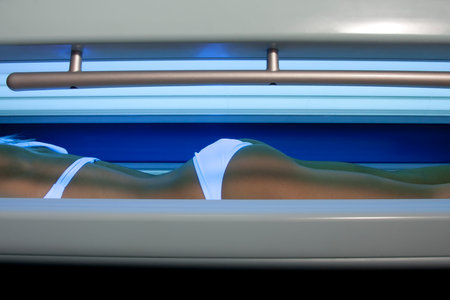 Beautiful slim blonde girl tans in the solariumの写真素材
