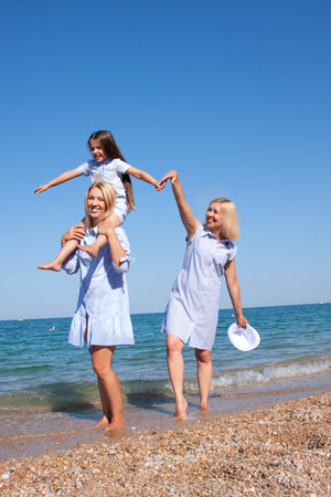 Beautiful Mom with daughter and grandmother relaxing and having fun on the beachの写真素材
