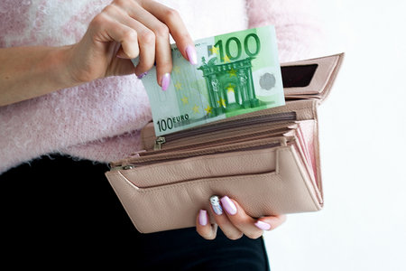 A woman pays 100 euros for a purchase, extends money from her wallet