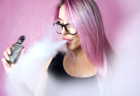 Beautiful stylish woman with pink hair in glasses vaping. On style.