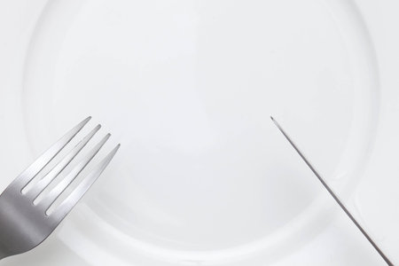 knife and fork above empty plateの写真素材
