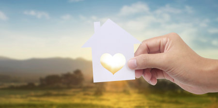 Hands holding paper house, family home and protecting insurance conceptの写真素材