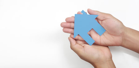 Hands holding paper house, family home and protecting insurance conceptの写真素材