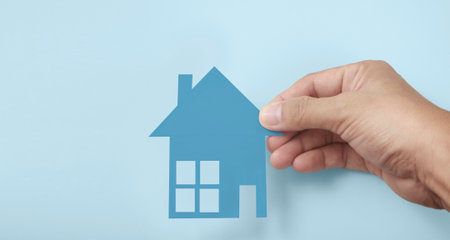 Hands holding paper house, family home and protecting insurance conceptの写真素材