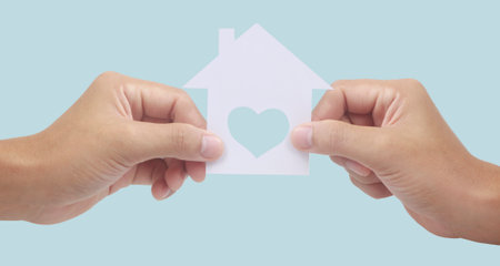 Hands holding paper house, family home and protecting insurance conceptの写真素材