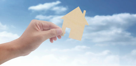 Hands holding paper house, family home and protecting insurance conceptの写真素材