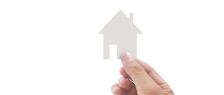 Hand holding paper house icon isolated on white background. Real estate concept.の写真素材
