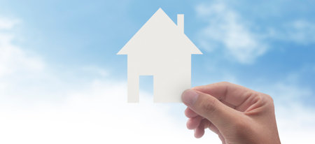 Hands holding paper house, family home and protecting insurance conceptの写真素材