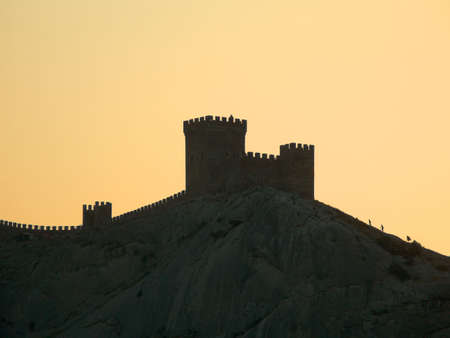 Silhouette of tower and wall on rock at sunsetの写真素材