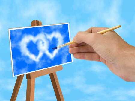 Hand with brush, blue sky and heart-shaped clouds on easelの写真素材