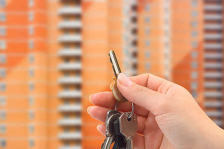 Hand with keys, building on backgroundの写真素材