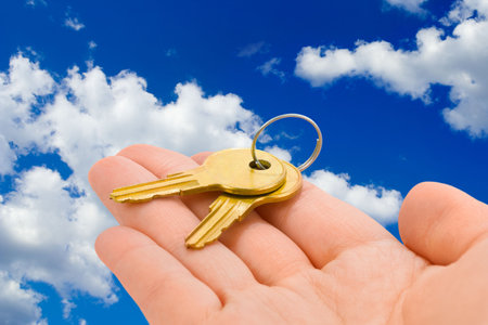 Hand giving keys, sky on backgroundの写真素材