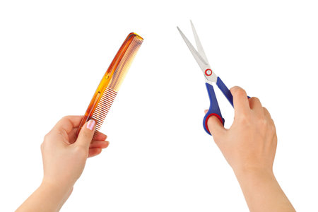 Hands with scissors and comb isolated on white backgroundの写真素材