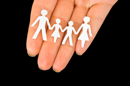 Paper family in hand isolated on black backgroundの写真素材