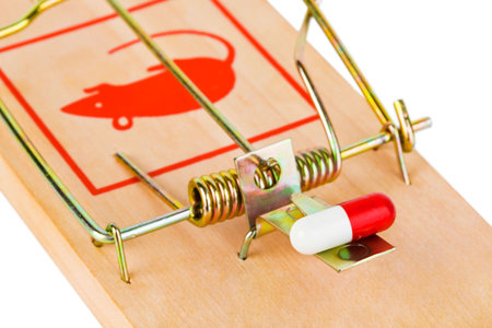 Mousetrap and pill isolated on white background