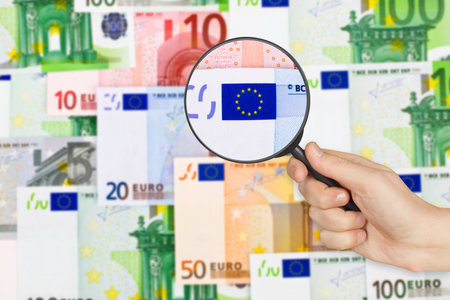 Money and magnifying glass in hand - business backgroundの写真素材