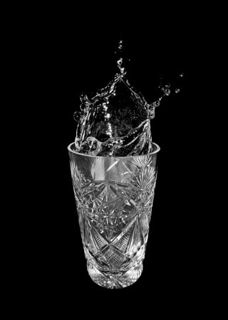 Glass of water and splashes isolated on black backgroundの写真素材