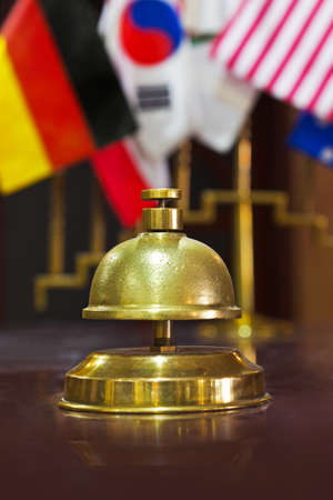Service ring bell on a hotel reception and flags on background