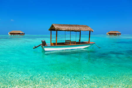 Boat and bungalow on Maldives island - nature travel backgroundのeditorial素材