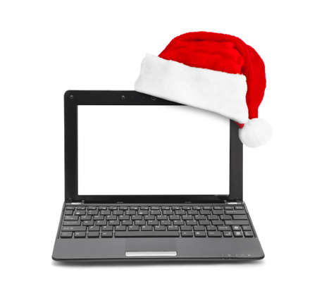 Notebook computer and Santa Claus red christmas hat isolated on white backgroundの写真素材