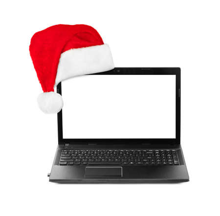 Notebook computer and Santa Claus red christmas hat isolated on white backgroundの写真素材