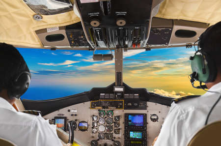 Pilots in the plane cockpit and sunset - transportation background
