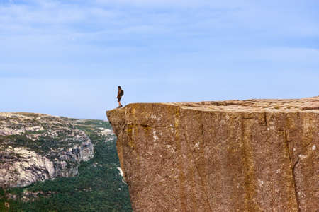 Lonely man standing on cliff Preikestolen in fjord Lysefjord - Norway - nature and travel backgroundの写真素材