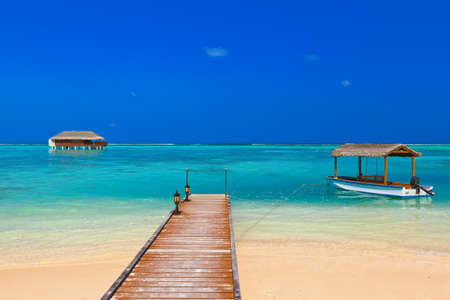 Boat and bungalow on Maldives island - nature travel background