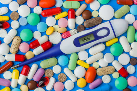 Pills and electronic thermometer (36.6 degrees) - abstract medical background