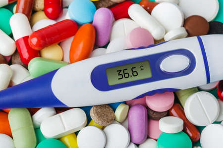 Pills and electronic thermometer (36.6 degrees) - abstract medical backgroundの写真素材