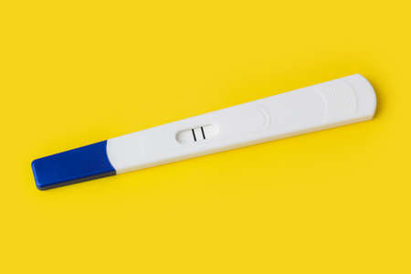 Pregnancy test (two lines) isolated on yellow background